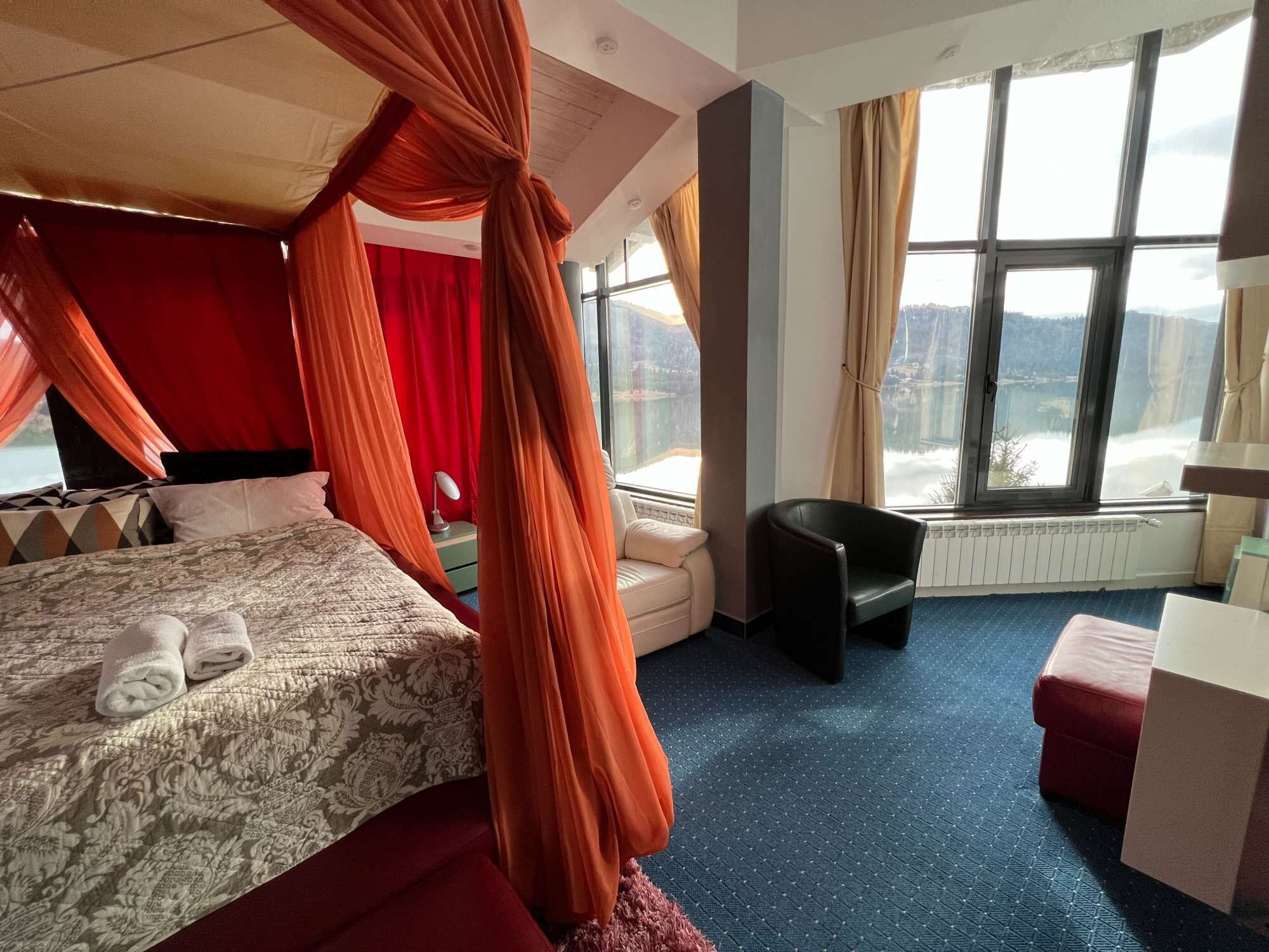 Ein Hotelzimmer mit Himmelbett, Seeblick und einem Vorhangfenster.