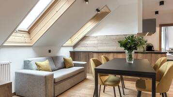 A modern loft with a dining area, a sofa, and a kitchen in the background.