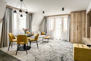A modern living room with a dining area, featuring a sofa, chairs, a coffee table, and a dining table.