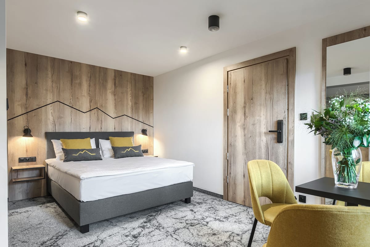 Ein modernes Schlafzimmer mit Bett, Nachttischen, einem Sessel und einer Holzwand.