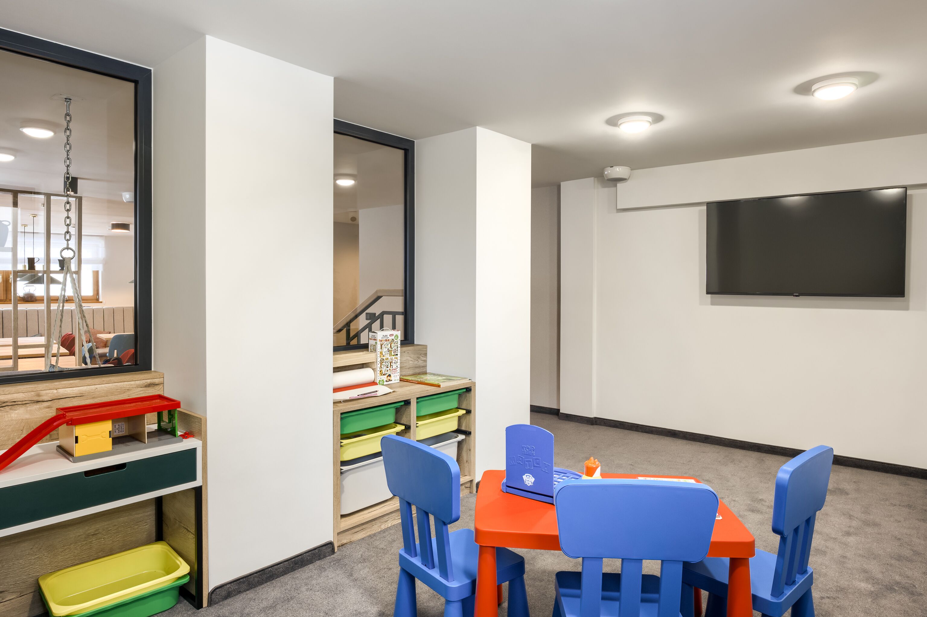A children's play area with a table, chairs, and storage bins.
