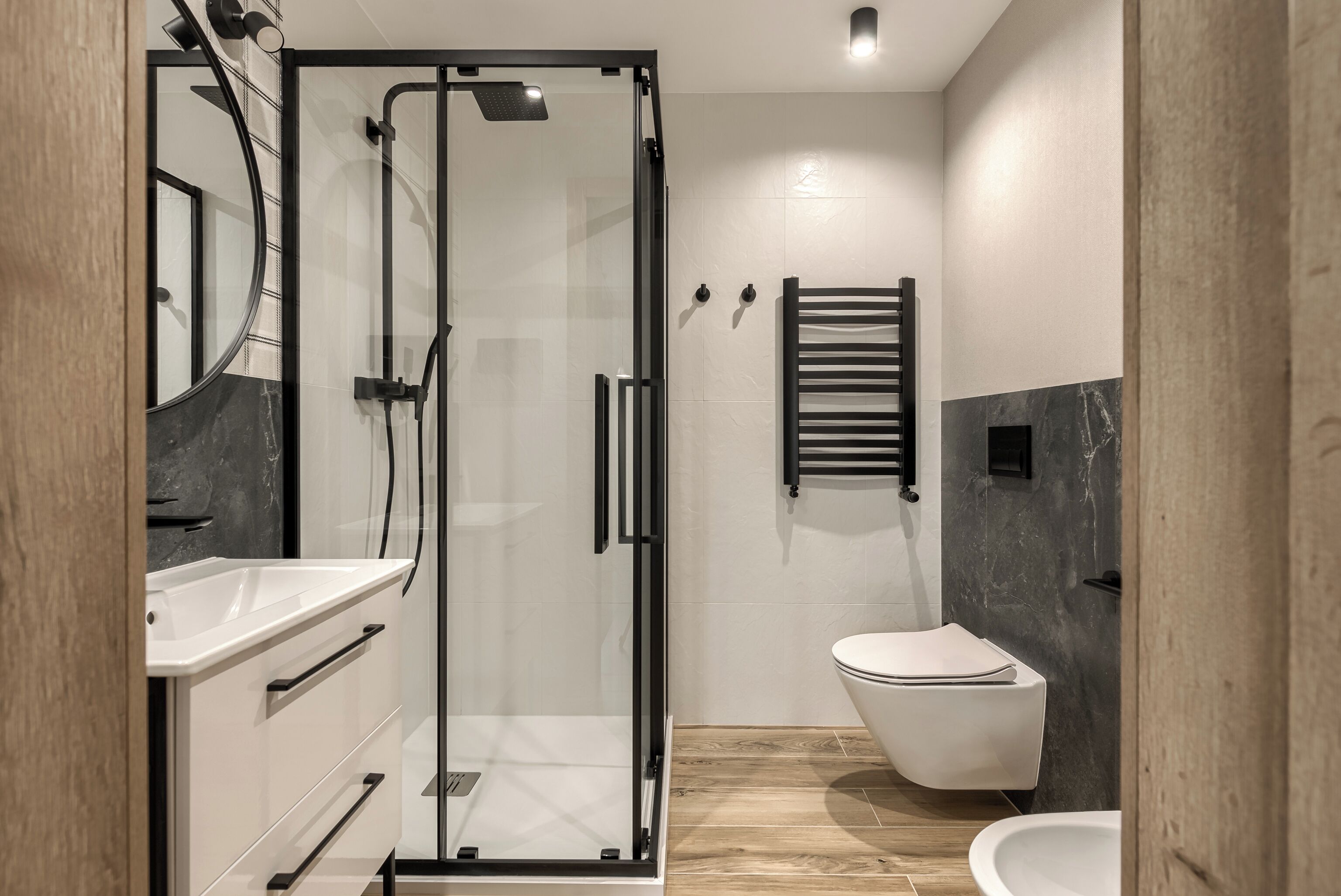 A modern bathroom with a glass-enclosed shower, a white toilet, and a vanity with a mirror.