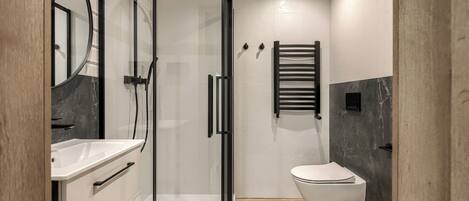A modern bathroom with a glass-enclosed shower, a white toilet, and a vanity with a mirror.