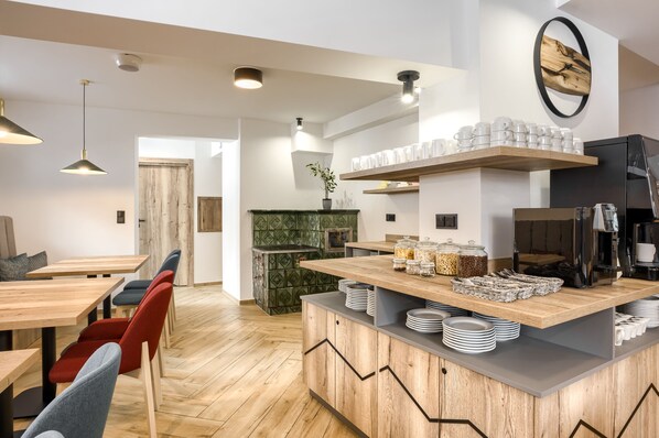 A modern kitchen with wooden countertops, a built-in coffee station, and a dining area with red chairs. - Szlakami 5 Dolin (Zakopane)