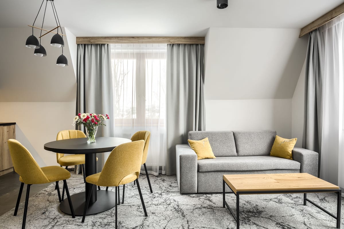 Ein modernes Wohnzimmer mit einem grauen Sofa, gelben Sesseln, einem runden Tisch und einem Holztisch.