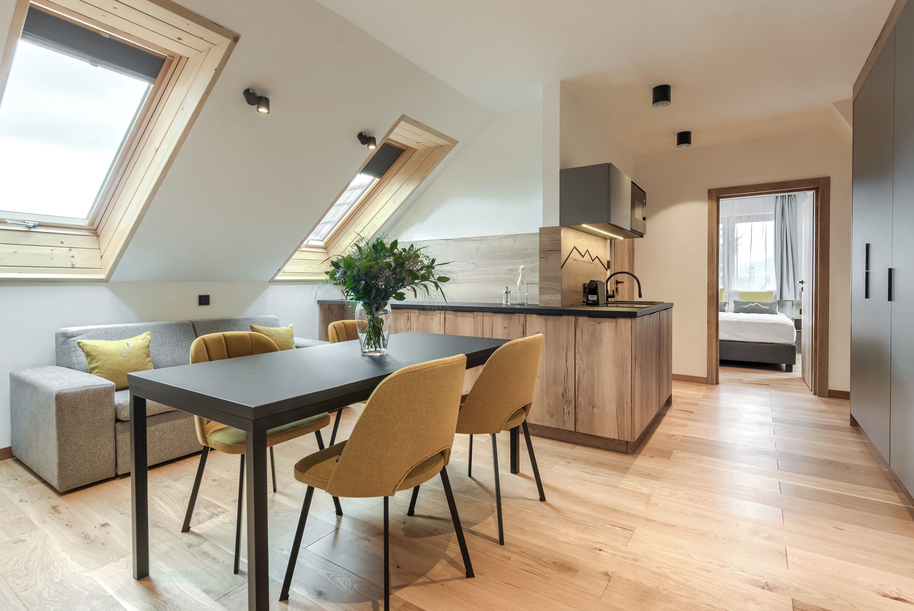 A modern loft apartment with a dining area, kitchenette, and a bedroom.