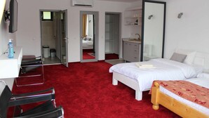 Ein Hotelzimmer mit rotem Teppich, einem Bett, einem Schreibtisch, einem Stuhl, einem Kleiderschrank und einem Spiegel.