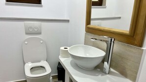 Un baño moderno con inodoro, lavamanos y espejo.