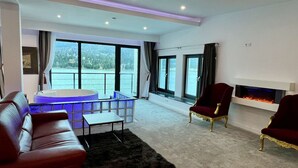 A modern living room with a leather sofa, a round coffee table, and a fireplace. - Room at lake Colibita with an incredible view over the lake with Jacuzzi. (Colibita)