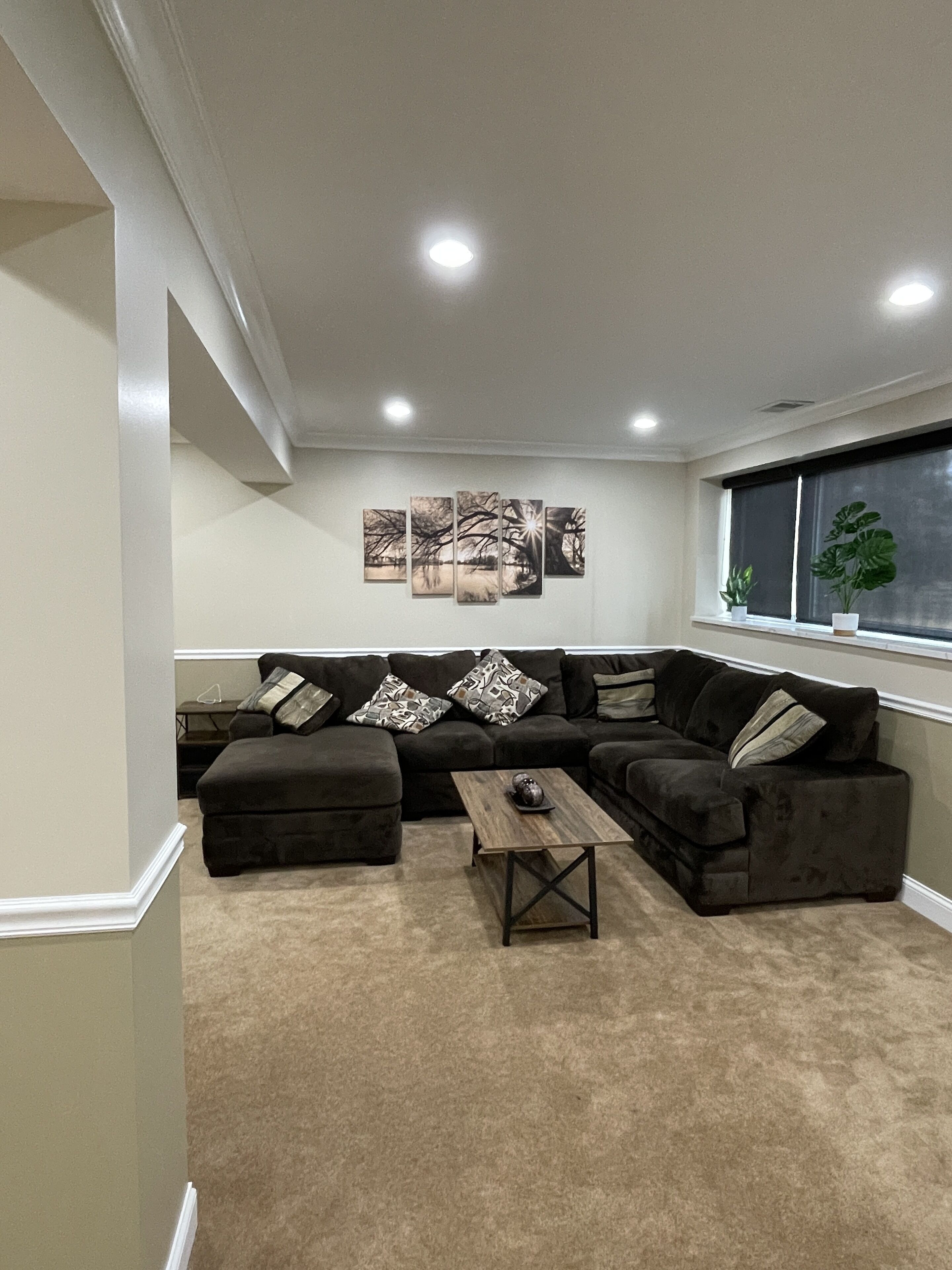 Ein Wohnzimmer mit Ecksofa, Couchtisch und Wandbild.