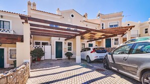 A covered parking area with two cars, a pergola, and a stone wall with seashells. - Casa Felix with pool (Albufeira)