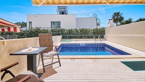 A rooftop pool area with a chair and table, a pool, and a building in the background. - Casa Felix with pool (Albufeira)