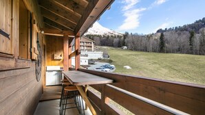 A wooden balcony with a view of a mountain and a grassy field. - Le Cerf des Alpages - Appt cosy pour 2 (La Giettaz)