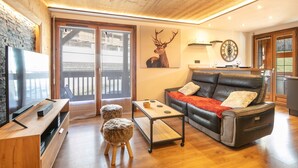 A modern living room with a wooden ceiling, a leather sofa, a wooden coffee table, and a mounted deer head. - Le Cerf des Alpages - Appt cosy pour 2 (La Giettaz)
