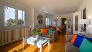 Ein helles Wohnzimmer mit einer Couch, einem Couchtisch und einem Essbereich mit Stühlen und einem Tisch.