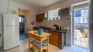Eine kleine Küche mit Kühlschrank, Holzschränken, einem Herd und einem Essplatz.
