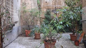 A courtyard with potted plants and a cobblestone floor. - Monart Hospitality Capodimonte (Naples)