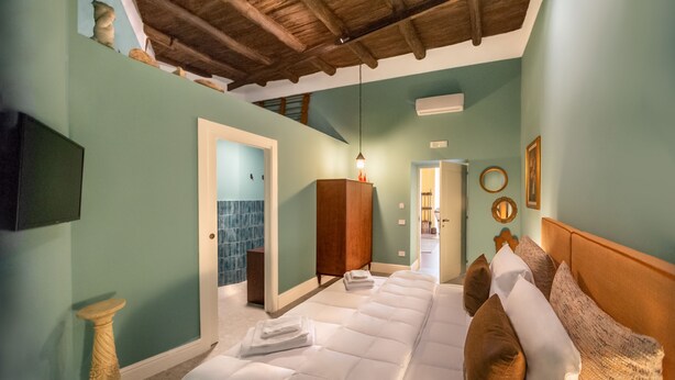 A spacious bedroom with a large bed, a wooden wardrobe, and a television on the wall. - Monart Hospitality Capodimonte (Naples)