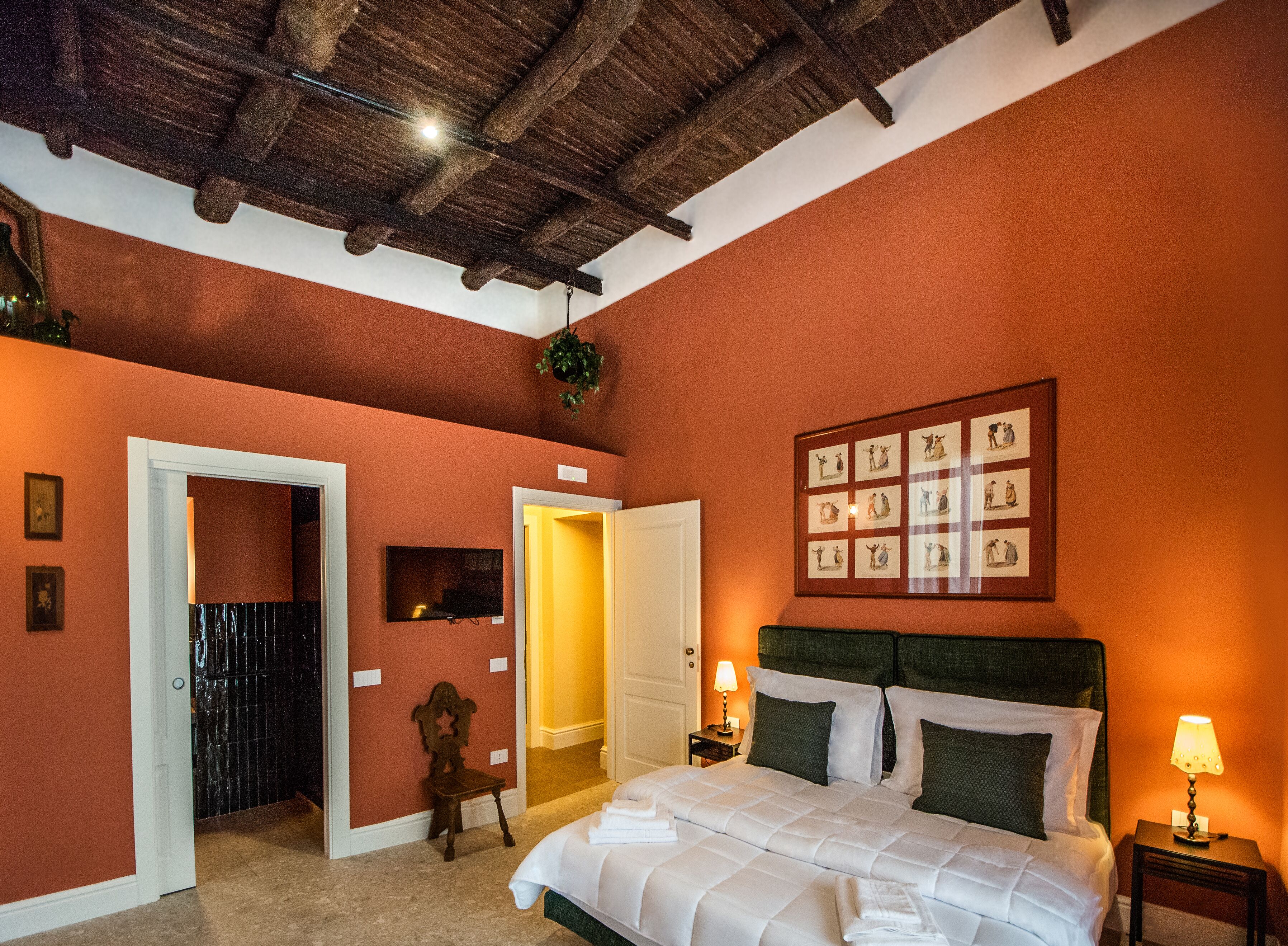 A bedroom with a wooden ceiling, a bed with white bedding, a nightstand with a lamp, and a framed picture on the wall.