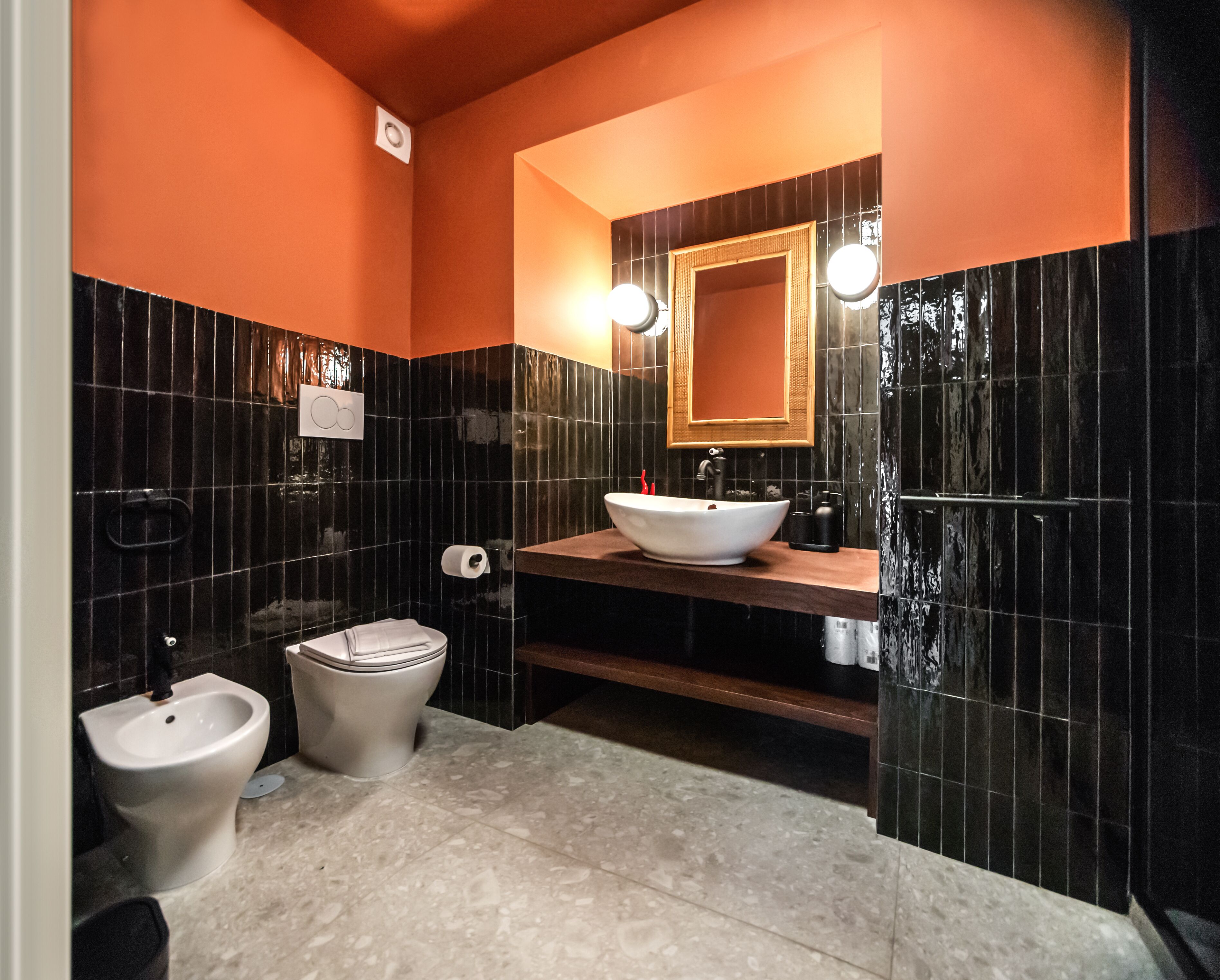 A modern bathroom with a bidet, toilet, and a large sink with a mirror above.