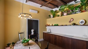 A kitchen with a marble table, wooden cabinets, and potted plants. - Monart Hospitality Capodimonte (Naples)