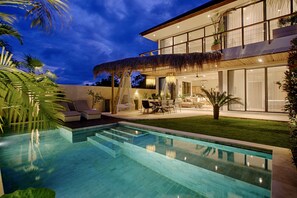 Ein modernes Haus mit Swimmingpool, Außenbereich und gepflegtem Rasen.
