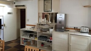 A kitchen with a refrigerator, a toaster, and a coffee maker. There is a sign above the refrigerator that reads "Breakfast." - Hellenic Hotel London by Saba (London)
