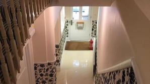 A staircase with a handrail leading to a landing. The landing has a door with a window, and the walls are decorated with floral patterns. - Hellenic Hotel London by Saba (London)