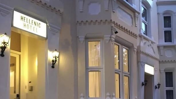 A hotel entrance with a sign reading "Hellenic Hotel," featuring a grand staircase with ornate railings and a lighted sign above the door. - Hellenic Hotel London by Saba (London)
