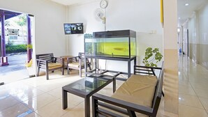 Ein Empfangsbereich mit Aquarium, Sitzgelegenheiten, einer Uhr und einem Fernseher.