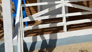 Una escalera de madera que lleva a una habitación con una puerta blanca y una silla azul.