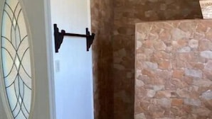 Un baño con pared de piedra, inodoro blanco y suelo de madera.