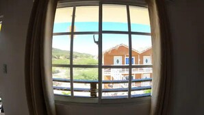 A room with a large window featuring a view of a building and landscape. - Villa Cruz Hotel & Restaurant Ocean View (buen hombre)