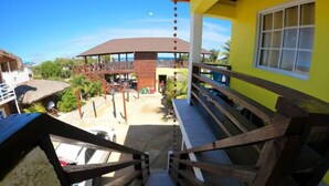 A staircase leading to a covered outdoor area with a view of a beach and a building with a thatched roof. - Villa Cruz Hotel & Restaurant Ocean View (buen hombre)