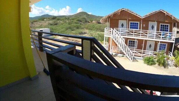 A wooden building with a balcony, surrounded by greenery and hills. - Villa Cruz Hotel & Restaurant Ocean View (buen hombre)
