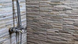 Ducha con un fondo de pared de piedra.