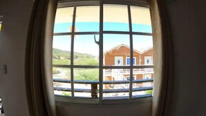 Una habitación con un ventanal que ofrece vistas a un edificio con balcón.