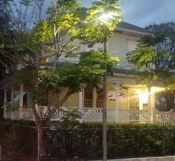 A two-story house with a porch, a sign indicating it's a house, and a fence in the foreground. - The Boutique Lagoon House (Fort Pierce)