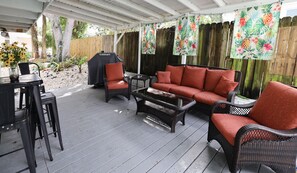 An outdoor patio with a covered seating area, a grill, and a table with chairs. - The Boutique Lagoon House (Fort Pierce)