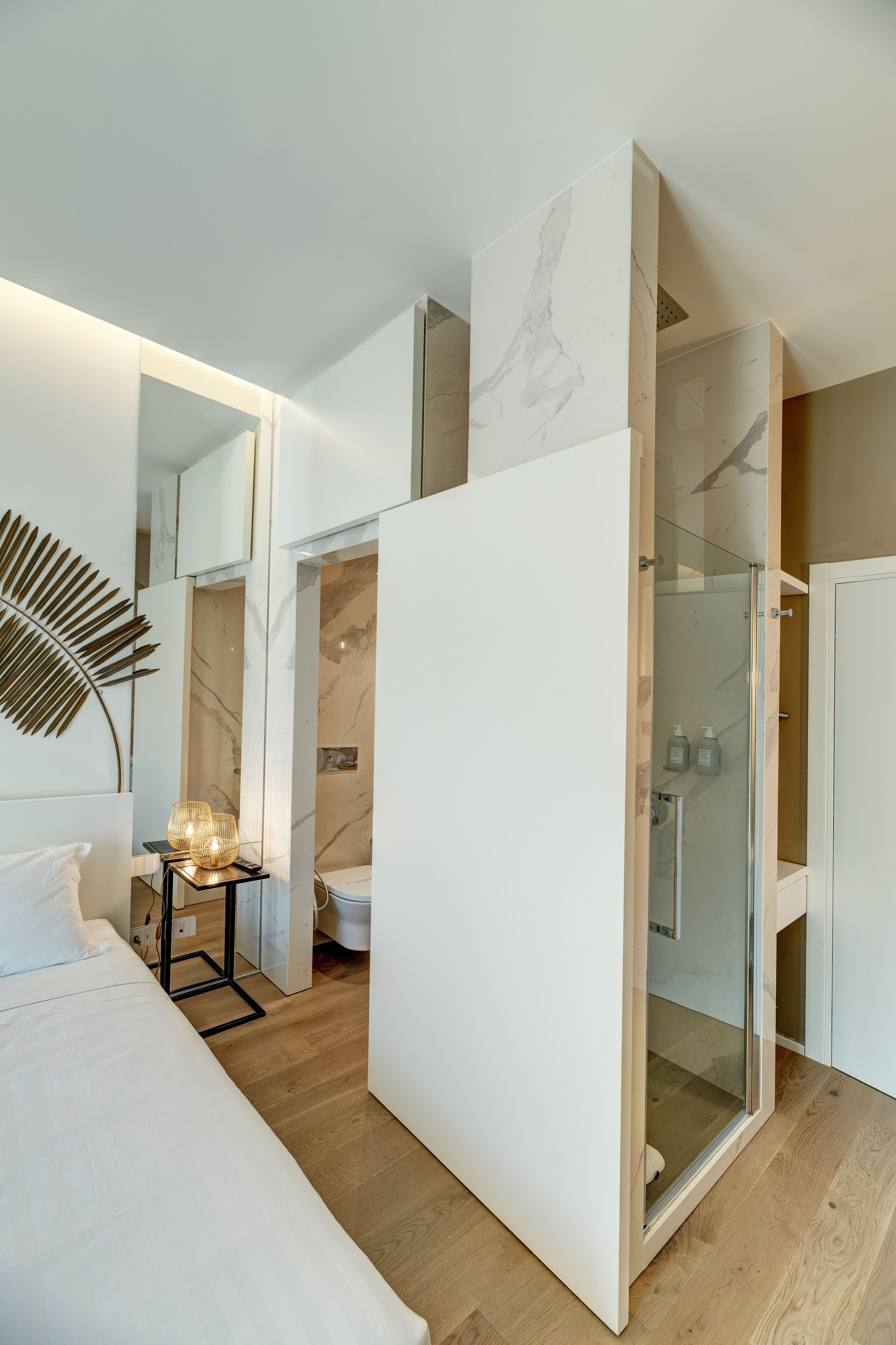 Un dormitorio moderno con cama, mesita de noche y ducha con cerramiento de vidrio.