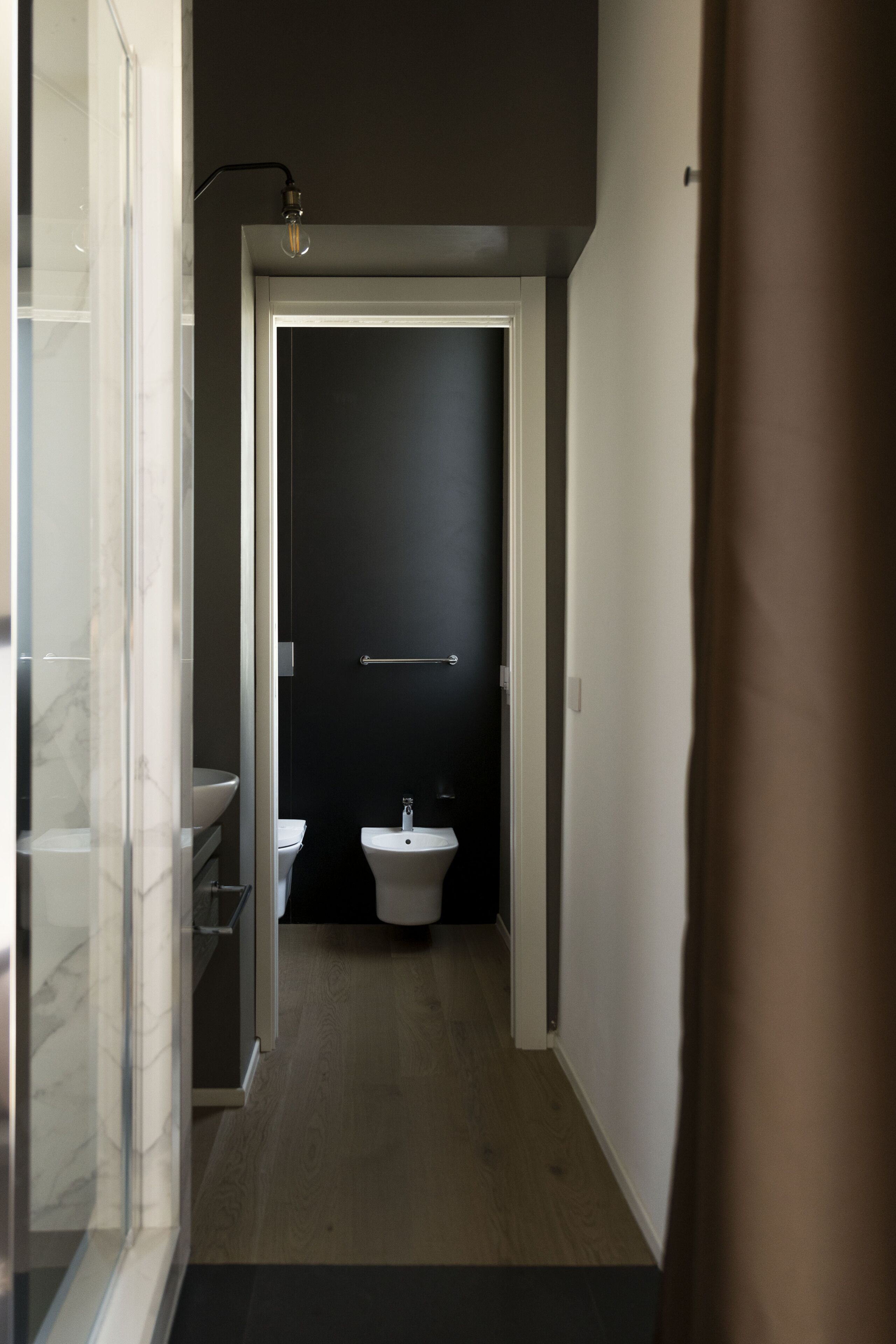 A narrow hallway leading to a bathroom with a toilet and sink.