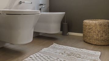 Een moderne badkamer met toilet, bad en een geweven kruk.