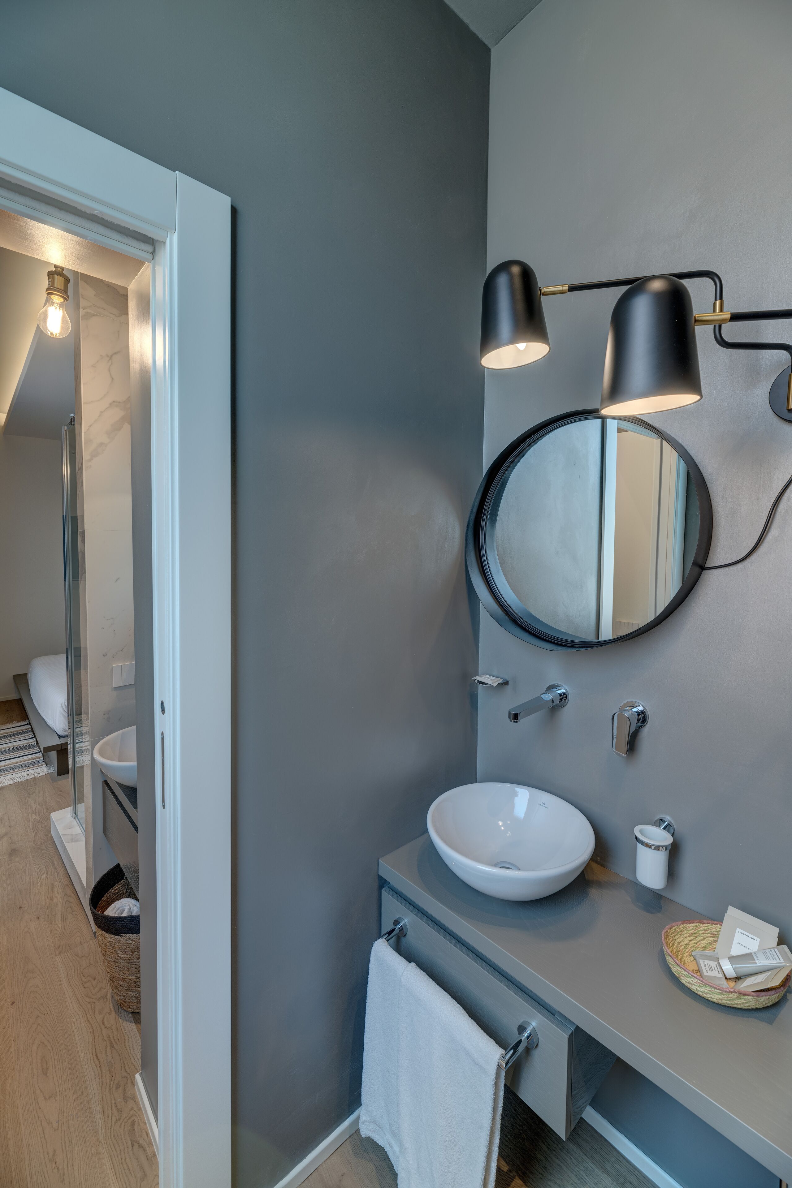 Ein modernes Badezimmer mit rundem Spiegel, einem Aufsatzwaschbecken und einem Handtuchhalter.