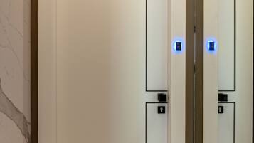 A white elevator with a number 3 on the door and a control panel with a light.