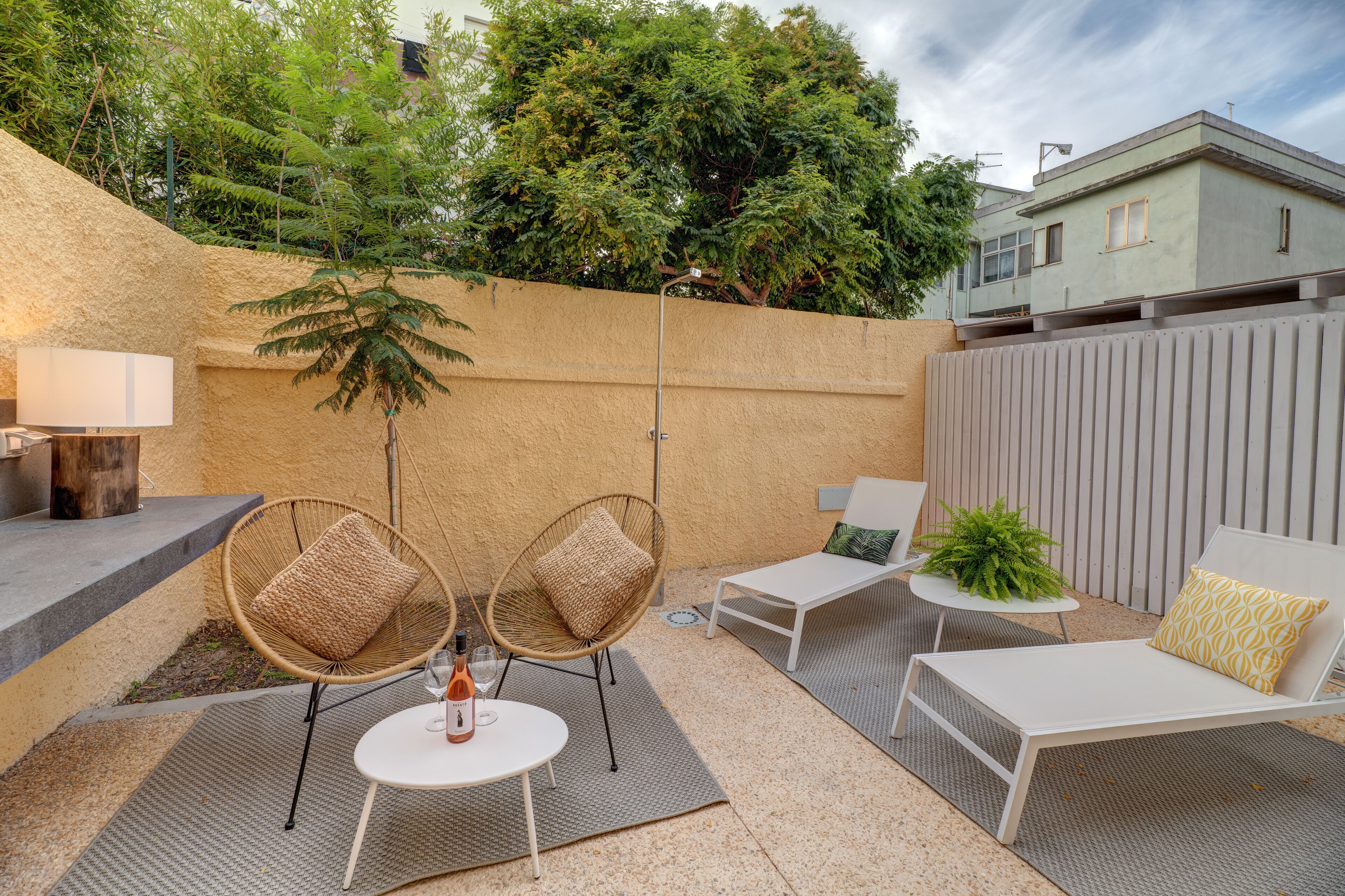 An outdoor patio with wicker chairs, a white table, and a potted plant.