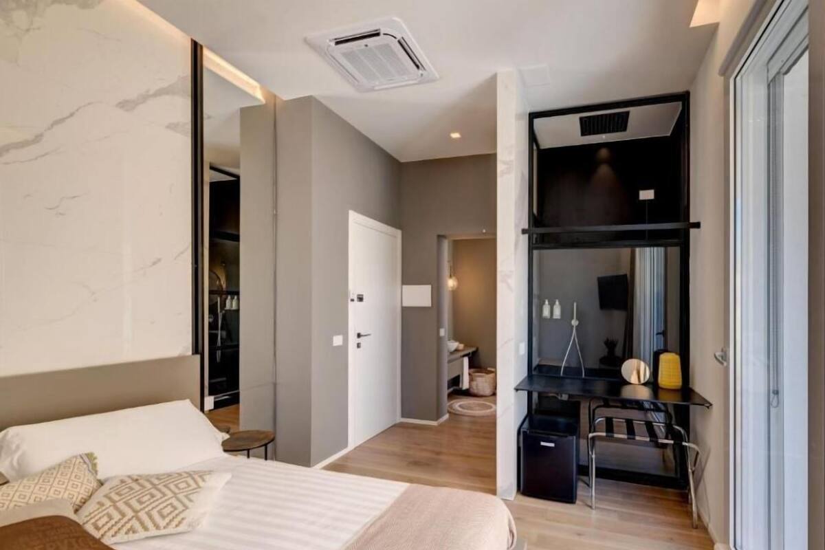A modern hotel room with a large bed, a desk, and a walk-in closet.