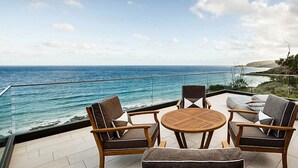 A terrace with a view of the ocean, featuring a round wooden table and two chairs. - Sea Ranch | Popular Coastal Retreat with Ocean View Bath (Wye River)