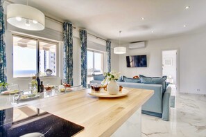 A modern kitchen with a wooden countertop, a dining table set with plates and glasses, and a vase with flowers.