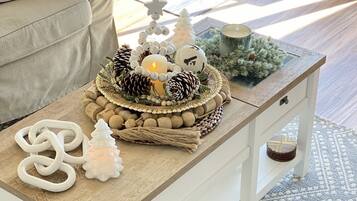 Un salon chaleureux avec une table basse décorative, agrémentée d’un sapin de Noël, de pommes de pin et d’une bougie allumée.