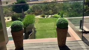 A balcony with a view of a beach, a grassy area, and a mountain in the distance.